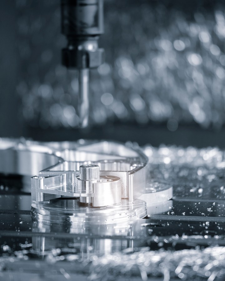 A milling cutter working on a clamped steel component.