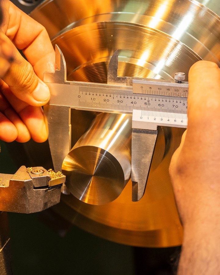 A cutter profiling a turned shaft held in a chuck.