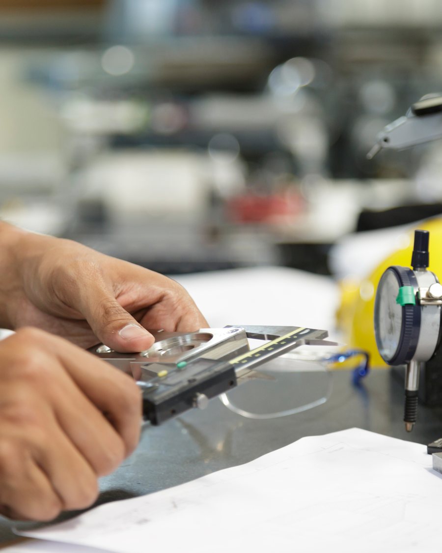 A technician measuring a machined part with a vernier caliper.