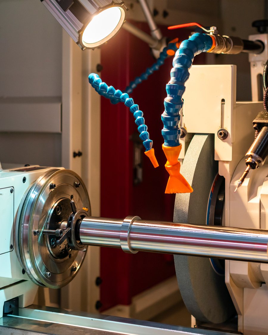 A cylindrical grinding machine finishing a steel shaft.