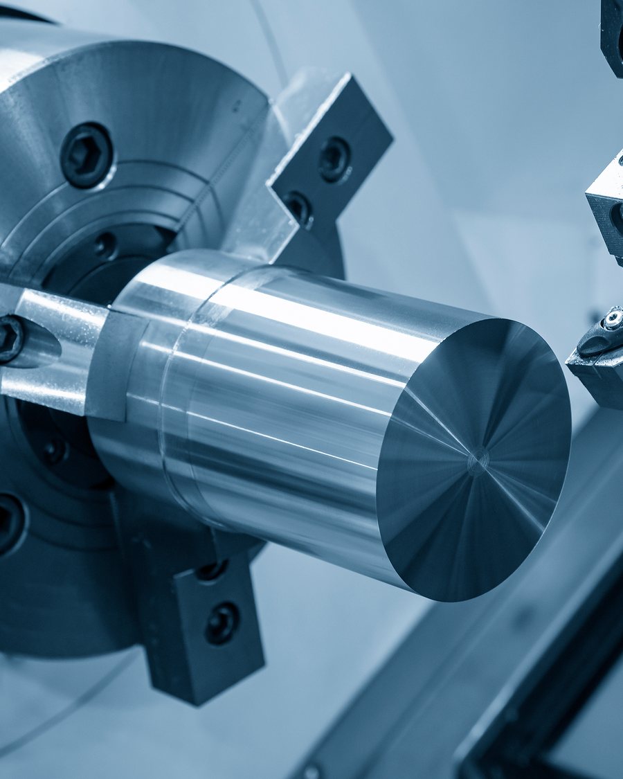 A CNC lathe chuck holding a turned steel shaft.
