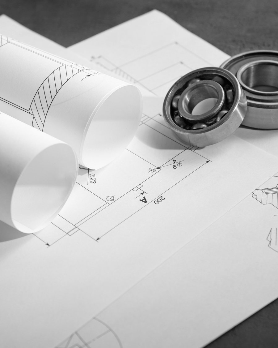 Rolled engineering drawings and bearings on a bench.