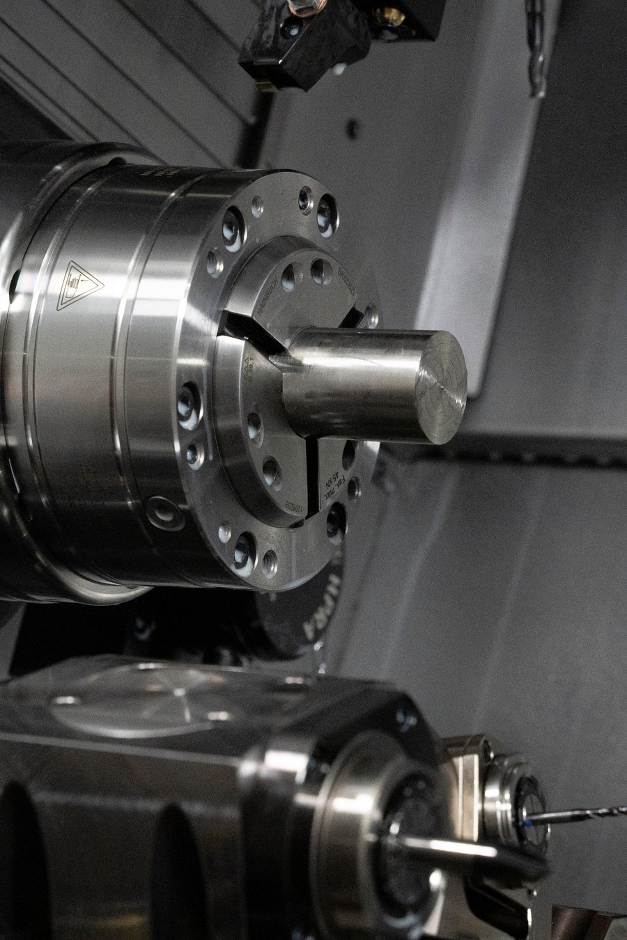 The spindle and chuck of a CNC lathe holding a workpiece.