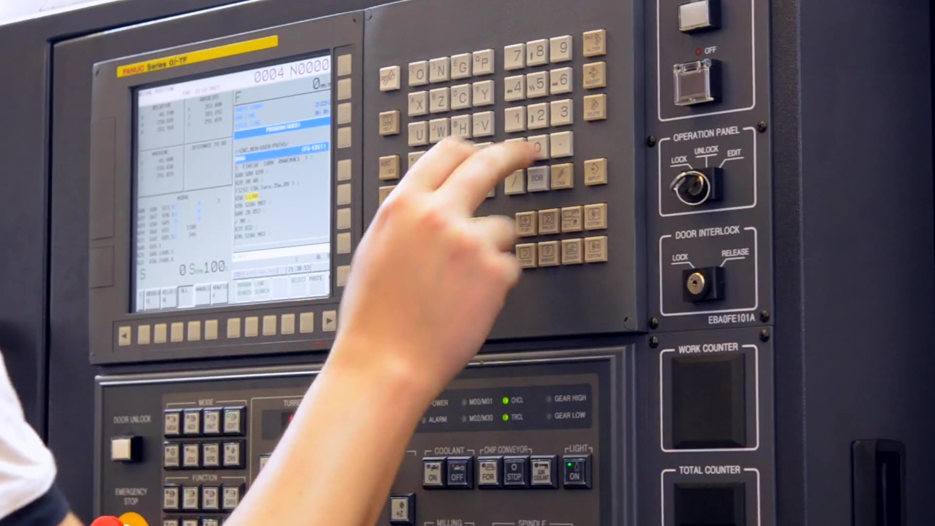 A hand on the control panel of a CNC machine.